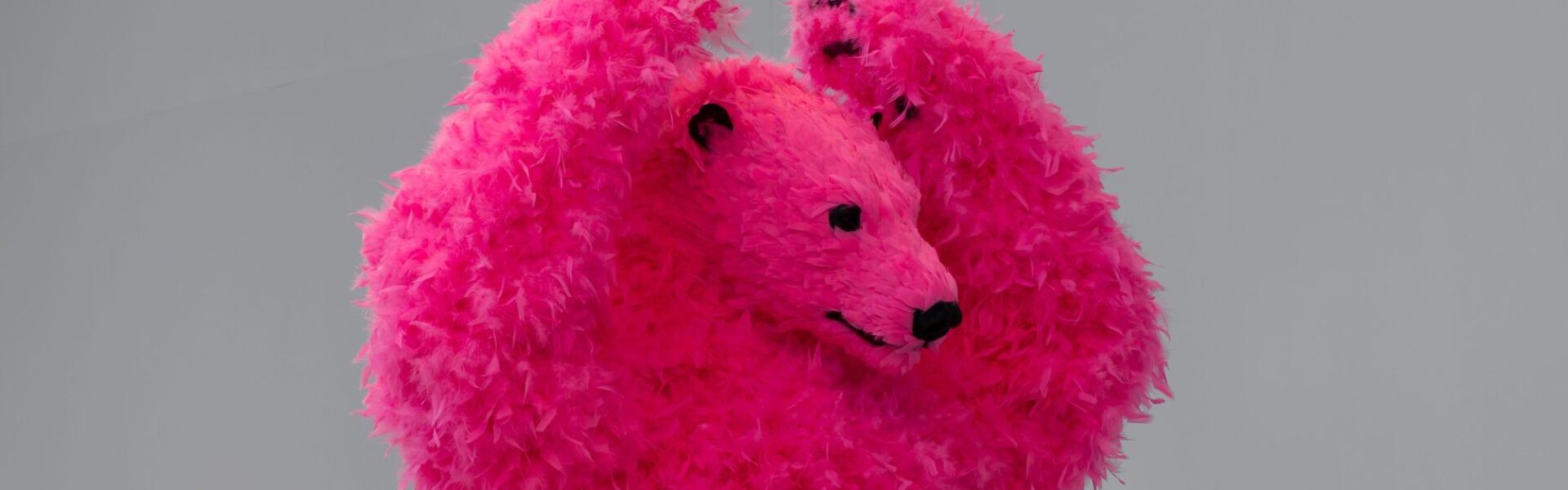 A sculpture of a dancing pink polar bear with feathers instead of fur.