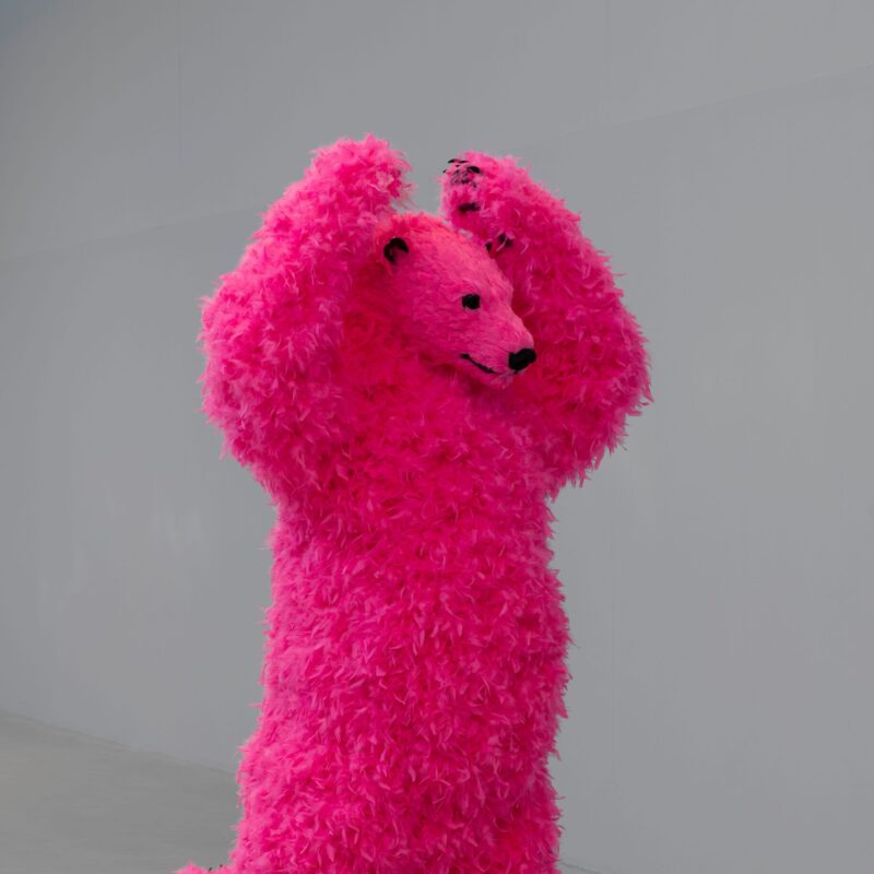 A sculpture of a dancing pink polar bear with feathers instead of fur.