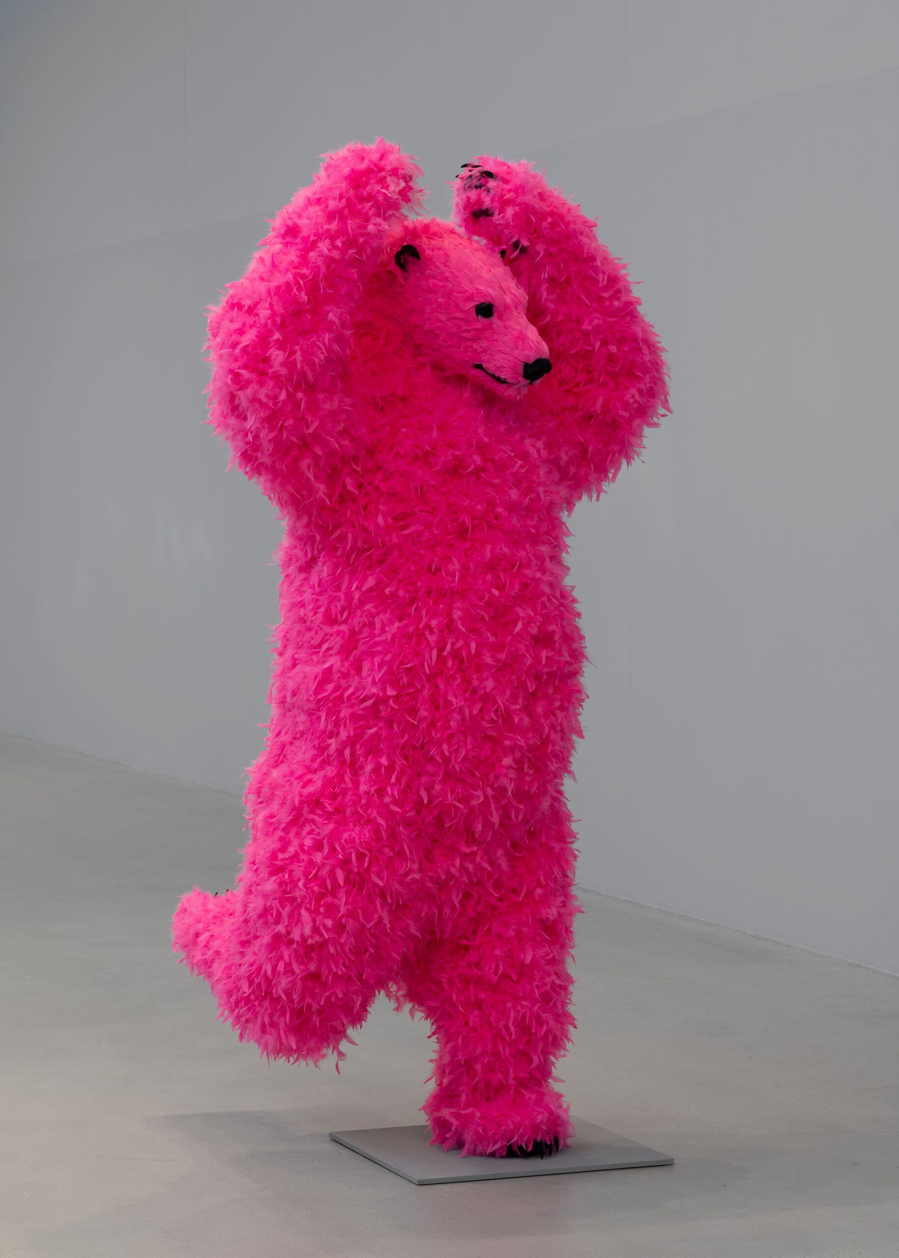 A sculpture of a dancing pink polar bear with feathers instead of fur.